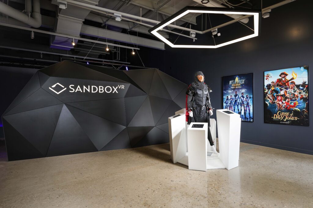 Sandbox VR lobby with a faceted wall, a central display featuring a suit of armor, and posters for Star Trek and Curse of Davy Jones.