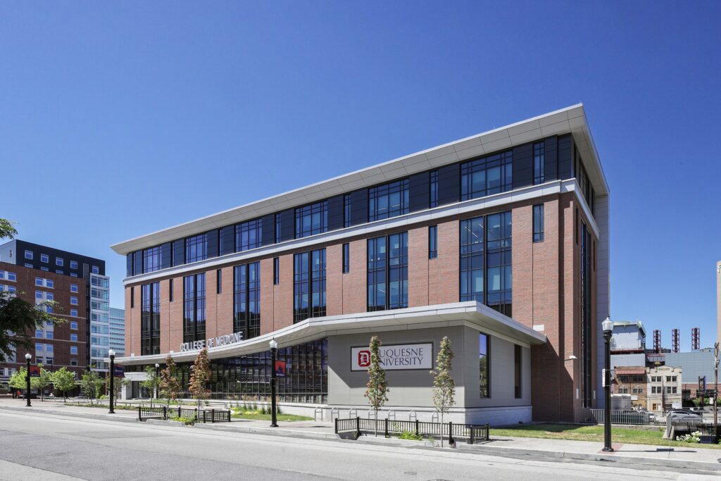 The Duquesne University College of Medicine building, a multi-story brick and glass structure on a city street.