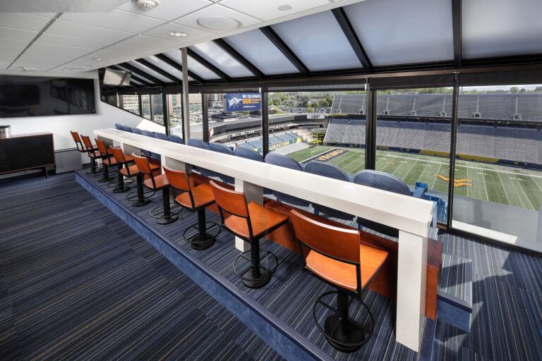 Luxury suite with counter seating overlooking a football stadium.