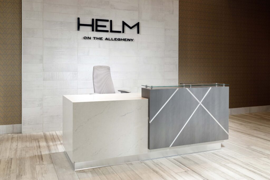 Reception desk with the logo “HELM ON THE ALLEGHENY” displayed on the wall behind it.