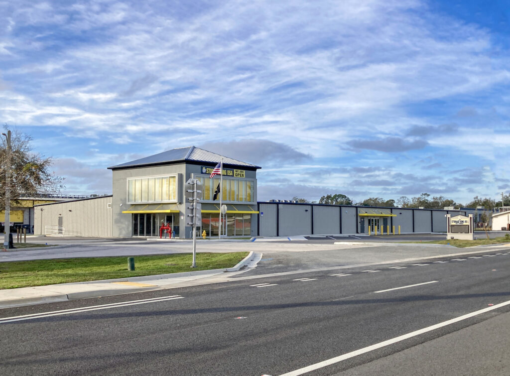 Storage King USA facility with a grey exterior, yellow awnings, and a corner entrance viewed from across a road.