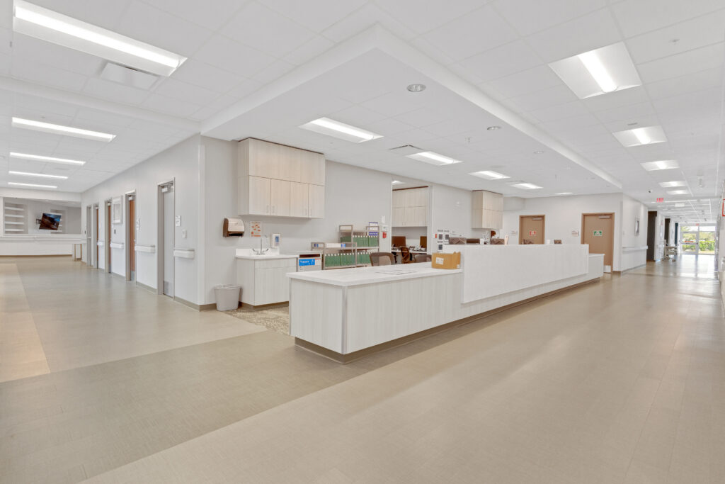 A view of a bright hospital nursing station with a long reception desk and hallway.
