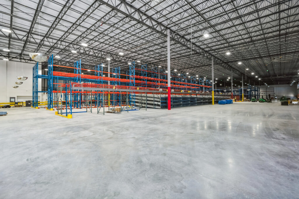 Empty warehouse interior with tall blue and orange industrial shelving units.