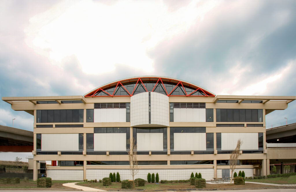 A symmetrical three-story building featuring a curved orange roof structure and a central protruding white facade.