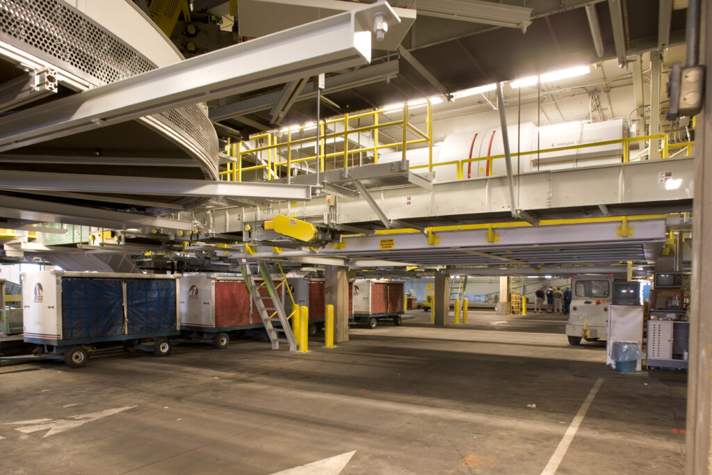 Baggage handling equipment and carts in an airport terminal service area.