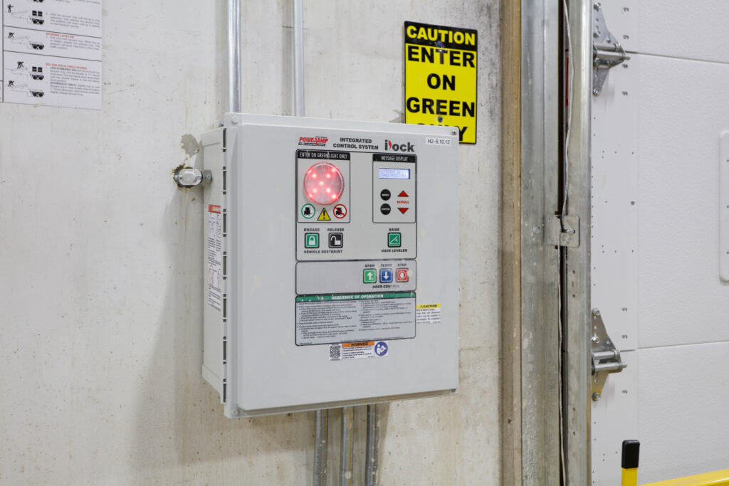 A Poweramp iDock integrated control system mounted on a wall next to a “Caution Enter on Green” sign.
