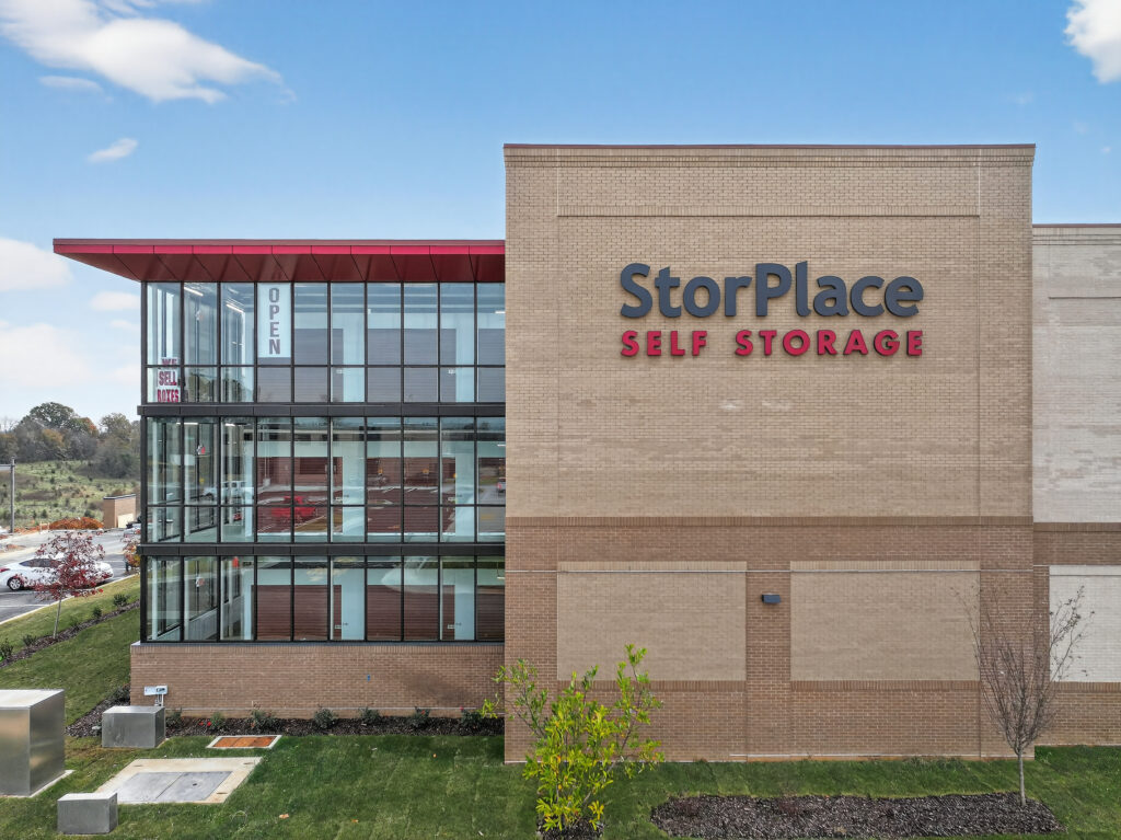 Exterior of a StorPlace Self Storage facility with glass-walled storage units and tan brick facade.