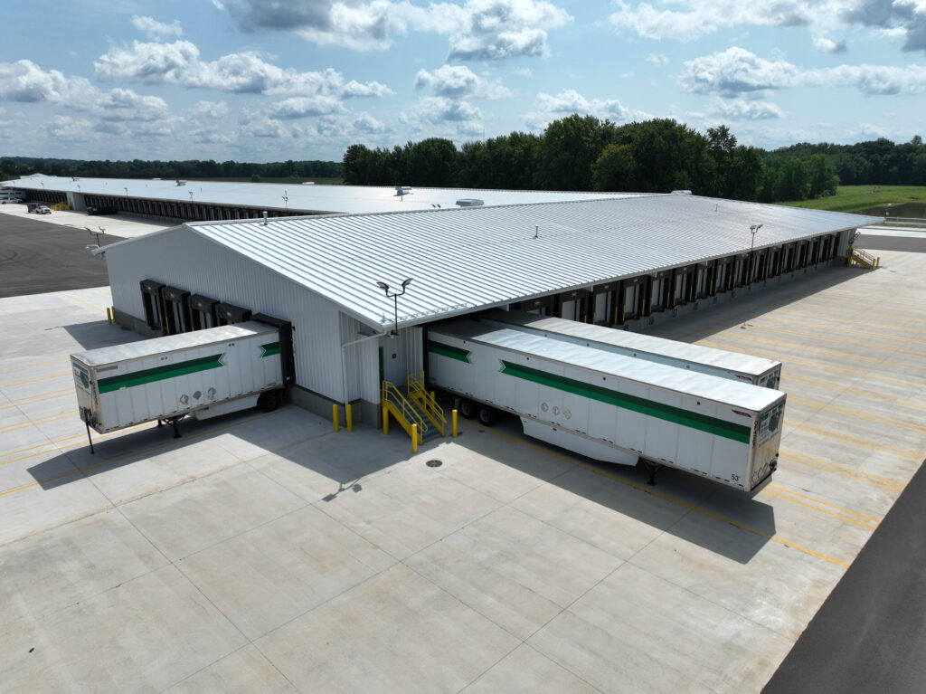 Aerial view of a large warehouse with two semi-trailers backed into loading docks.