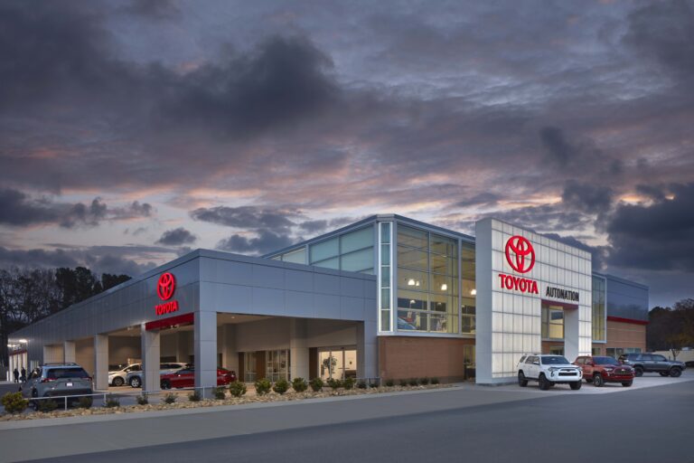 Toyota dealership building with several cars parked in the lot at dusk.