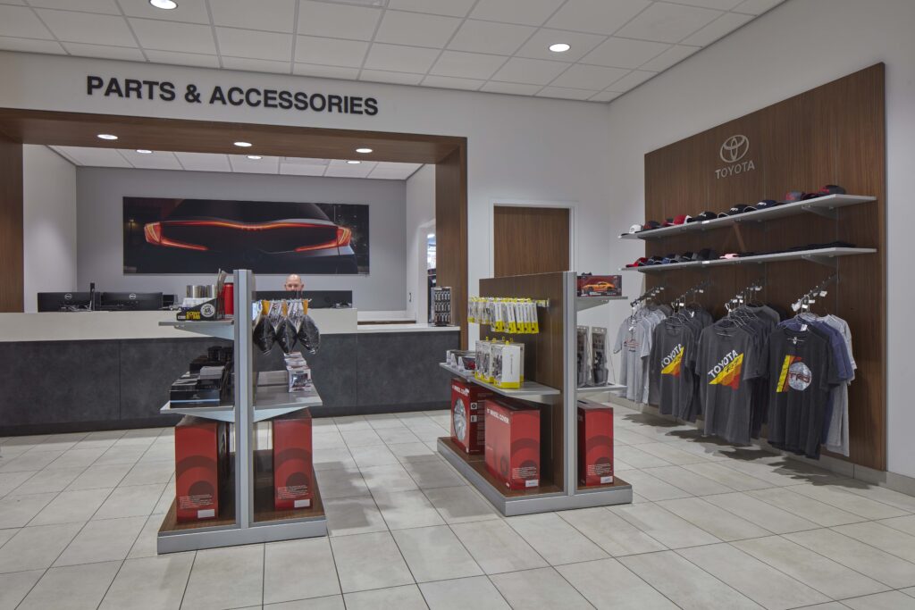 Toyota dealership parts and accessories department with merchandise displays, shelves of apparel, and a service desk.