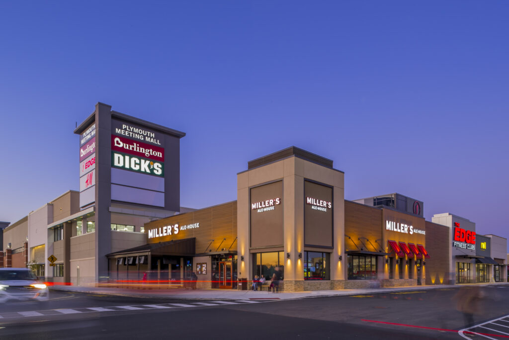 Plymouth Meeting Mall exterior at dusk, featuring a Miller’s Ale House, Burlington, and Dick’s Sporting Goods.
