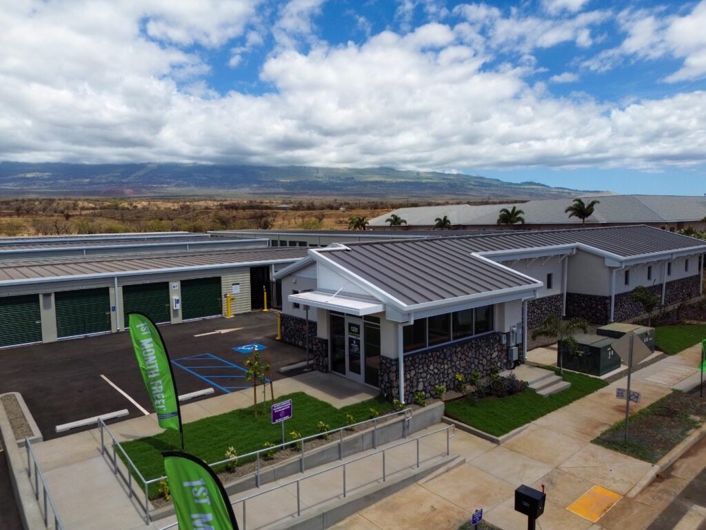An aerial view of a self-storage facility with a stone and gray exterior, featuring a customer office and multiple storage units with roll-up doors.