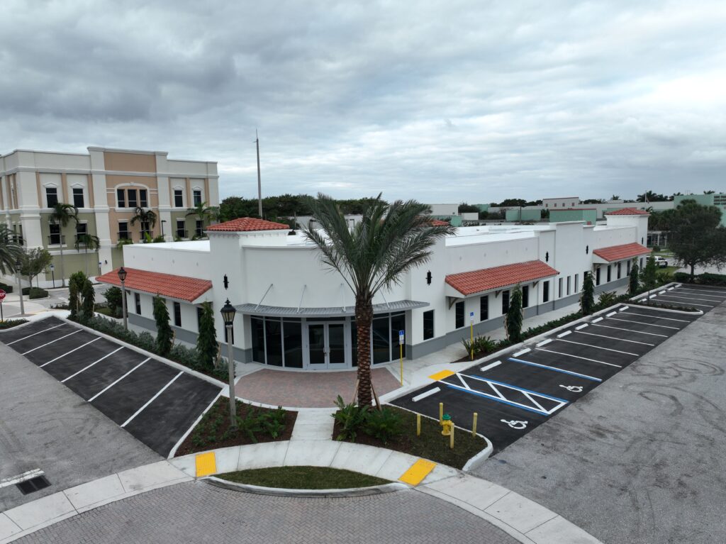 An aerial view of a single-story commercial building with a terracotta-tiled roof and an adjacent parking lot.
