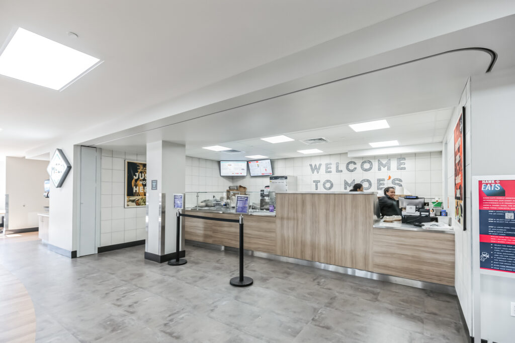 The service counter of a Moe’s Southwest Grill restaurant with a “Welcome to Moe’s” sign on the back wall.