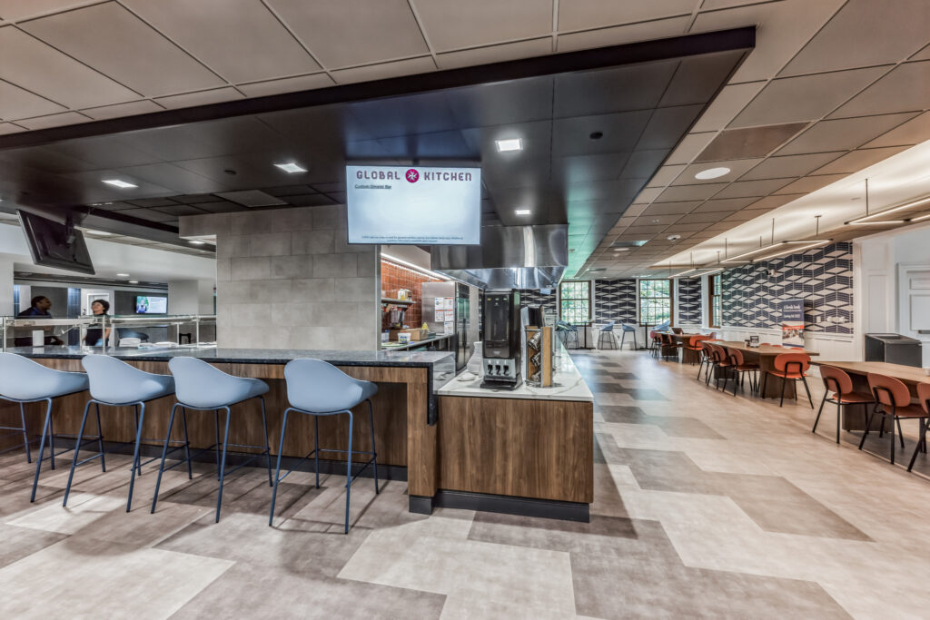 Global Kitchen dining area with a counter, blue bar stools, and a seating area with tables and chairs.