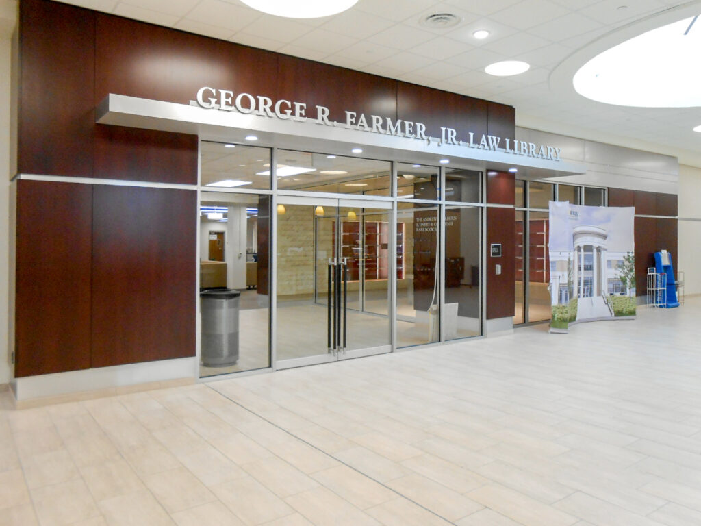Entrance to the George R. Farmer, Jr. Law Library with glass doors and a large sign in the lobby.