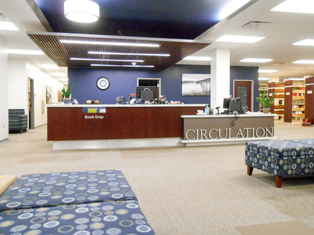 Circulation desk at a library with a sign that reads “CIRCULATION” and a “Book Drop” slot.