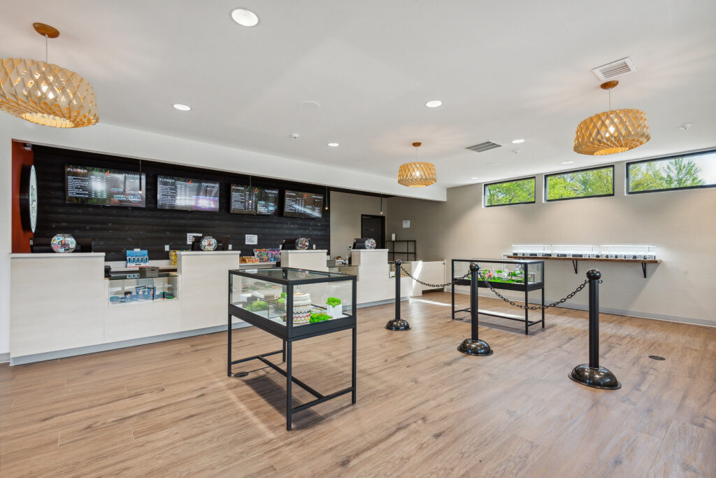 Interior view of a retail cannabis store with service counters, glass display cases, and digital menu screens on the wall.