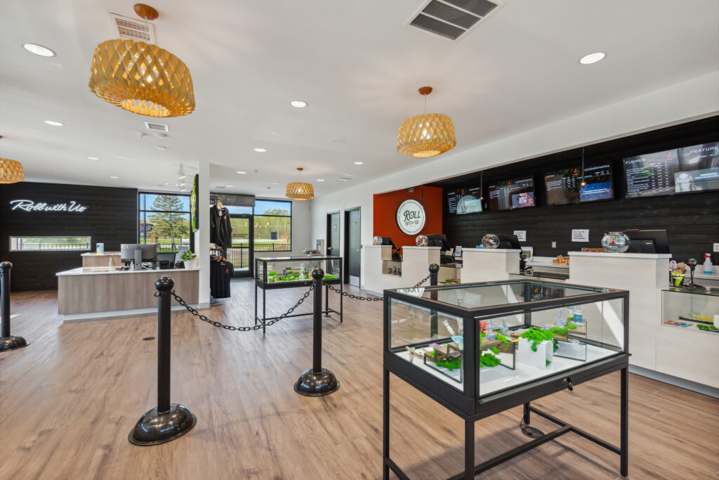 Interior of a retail store with glass product display cases, a service counter, and menu screens on the wall.