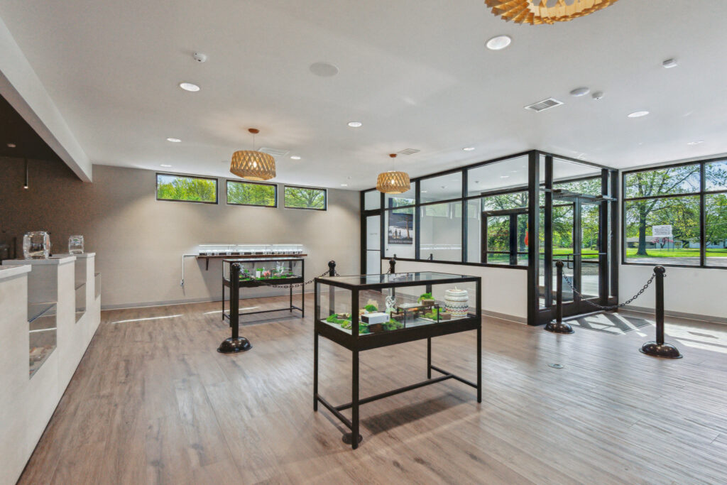 Interior of a gallery space with two glass display cases and wooden flooring.