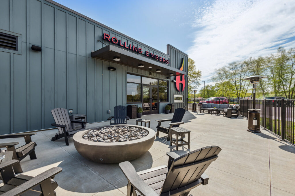 Outdoor patio at Rolling Embers featuring Adirondack chairs arranged around a circular stone fire pit.