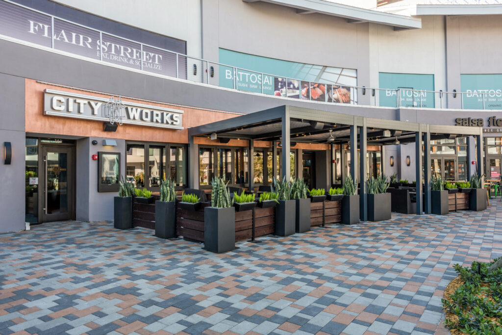 City Works restaurant exterior with outdoor patio seating and signage for neighboring businesses Flair Street and Battosai.