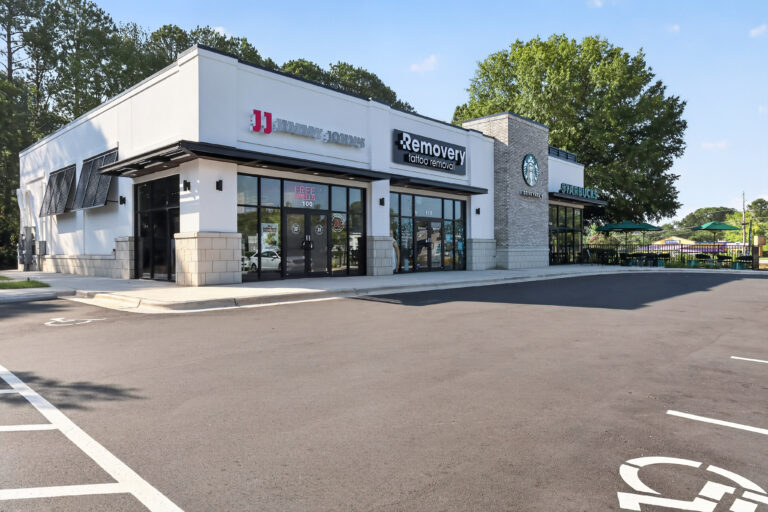 A strip mall containing a Jimmy John’s, a Removery tattoo removal clinic, and a Starbucks with a drive-thru.