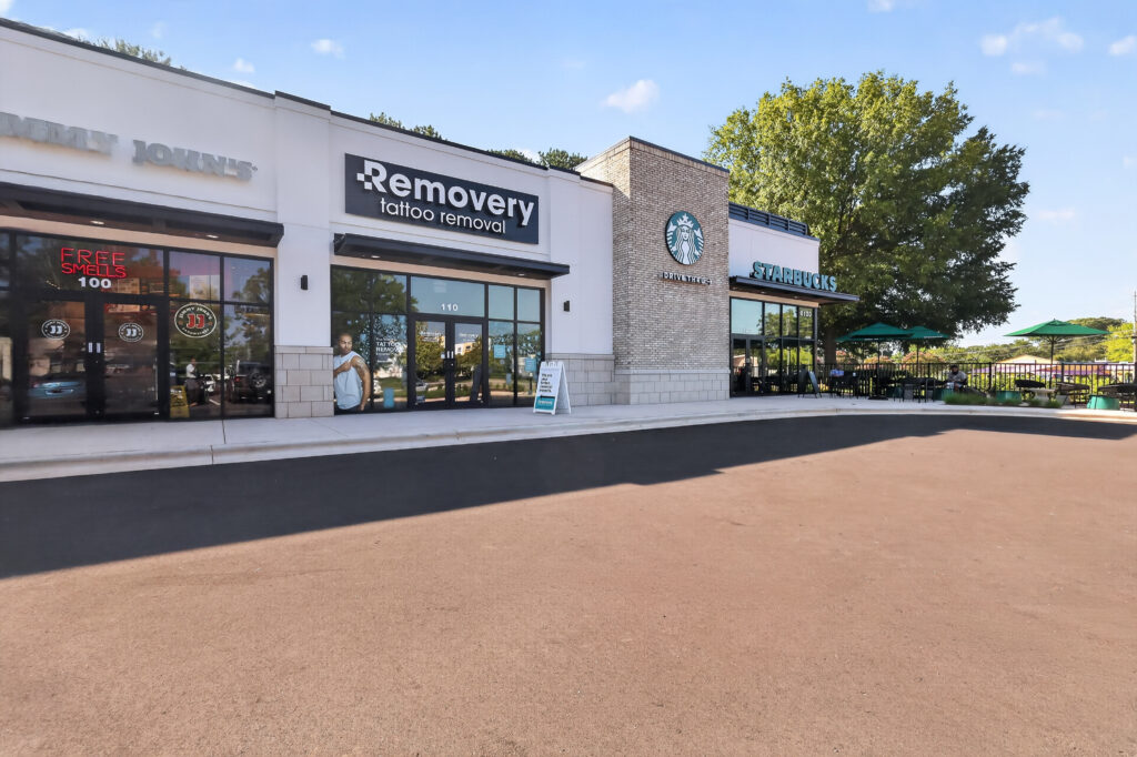 A storefront row featuring Jimmy John’s, Removery tattoo removal, and a Starbucks with a drive-thru.