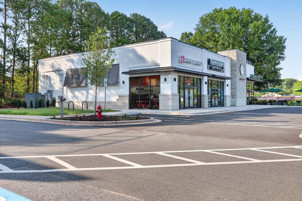 A strip mall building featuring a Jimmy John’s, Removery, and Starbucks, with an empty parking lot in the foreground.