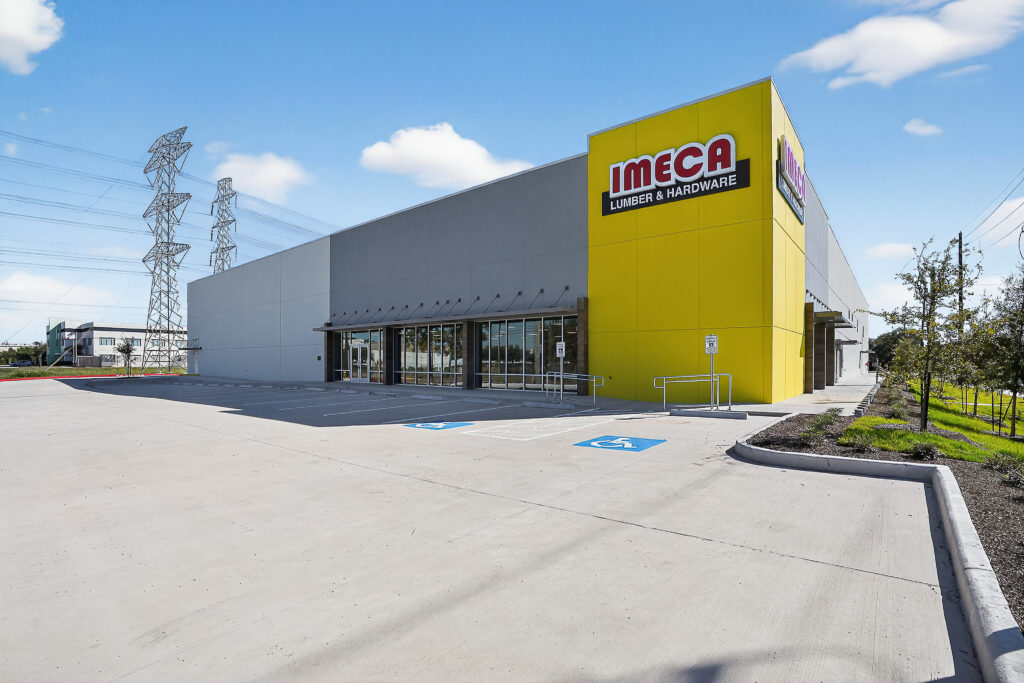 Exterior of an Imeca Lumber & Hardware store building with a large parking lot and handicap-accessible parking spaces.