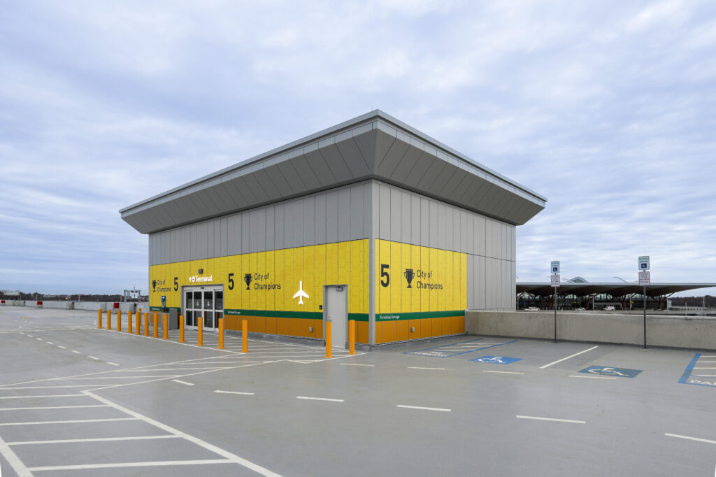 A bright yellow and grey parking garage terminal labeled “City of Champions” at an airport.