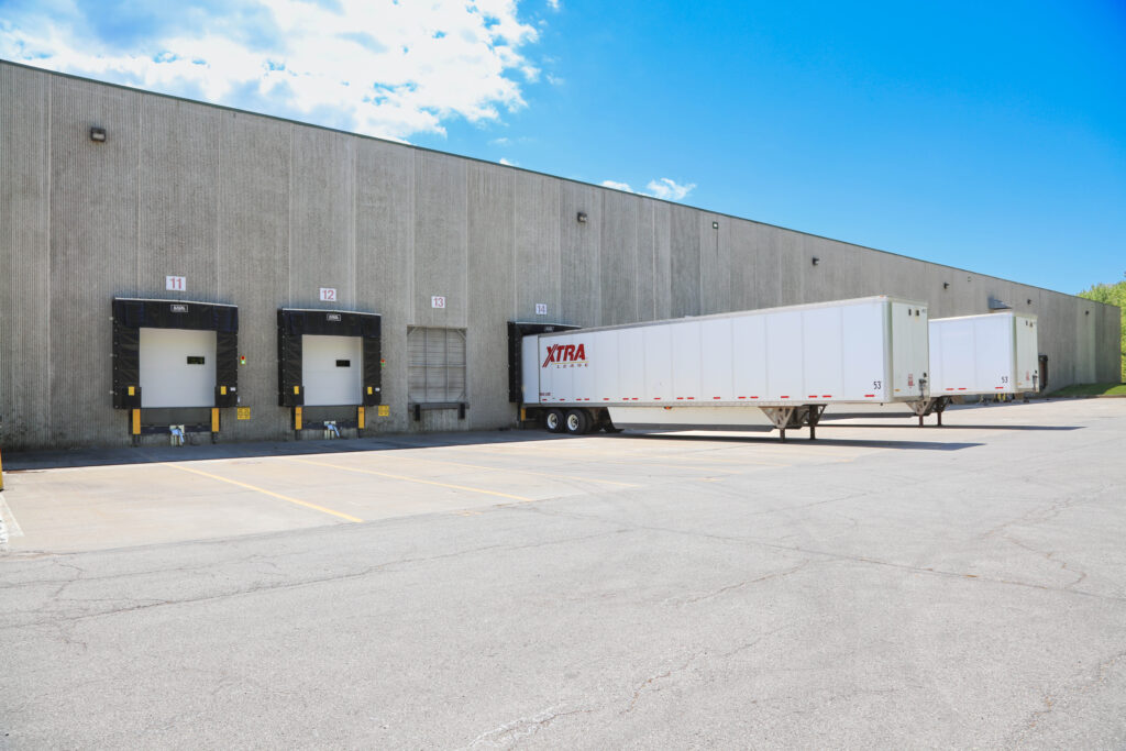Two semi-trailers docked at a warehouse loading bay.