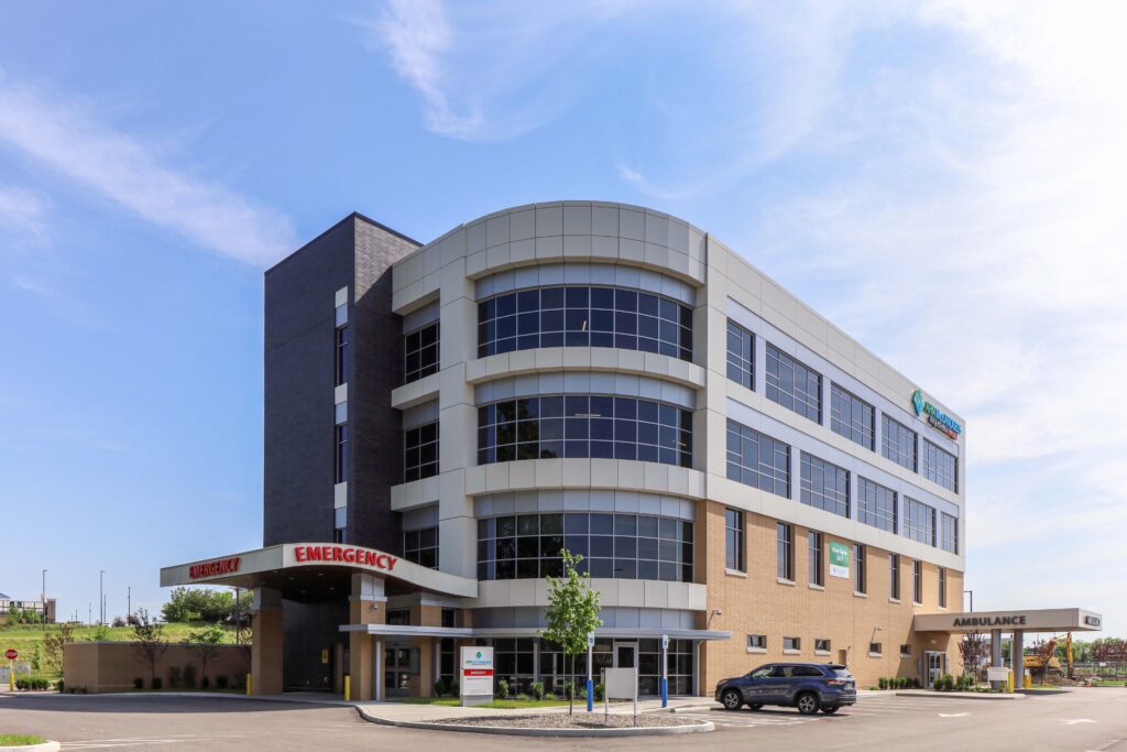 A multi-story hospital building with an emergency room entrance and a separate ambulance bay.