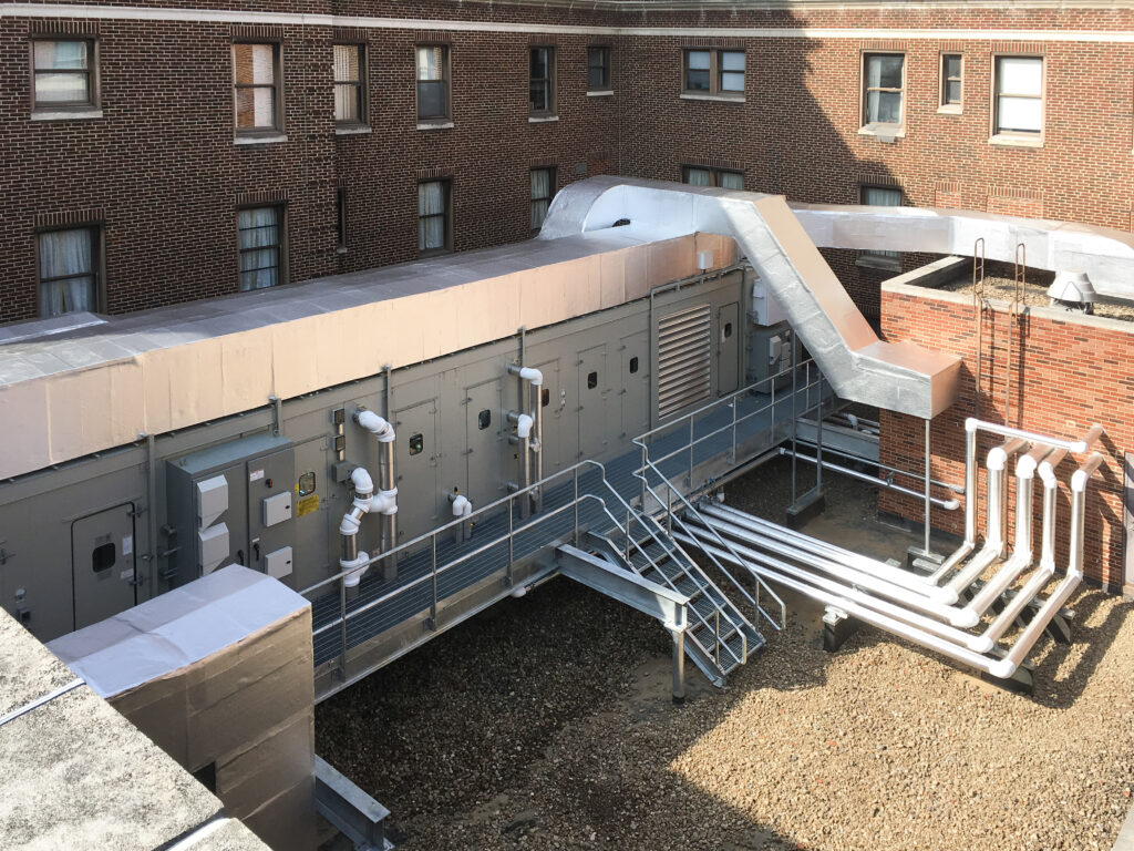 Industrial HVAC unit on a building roof with connected ductwork and pipes.
