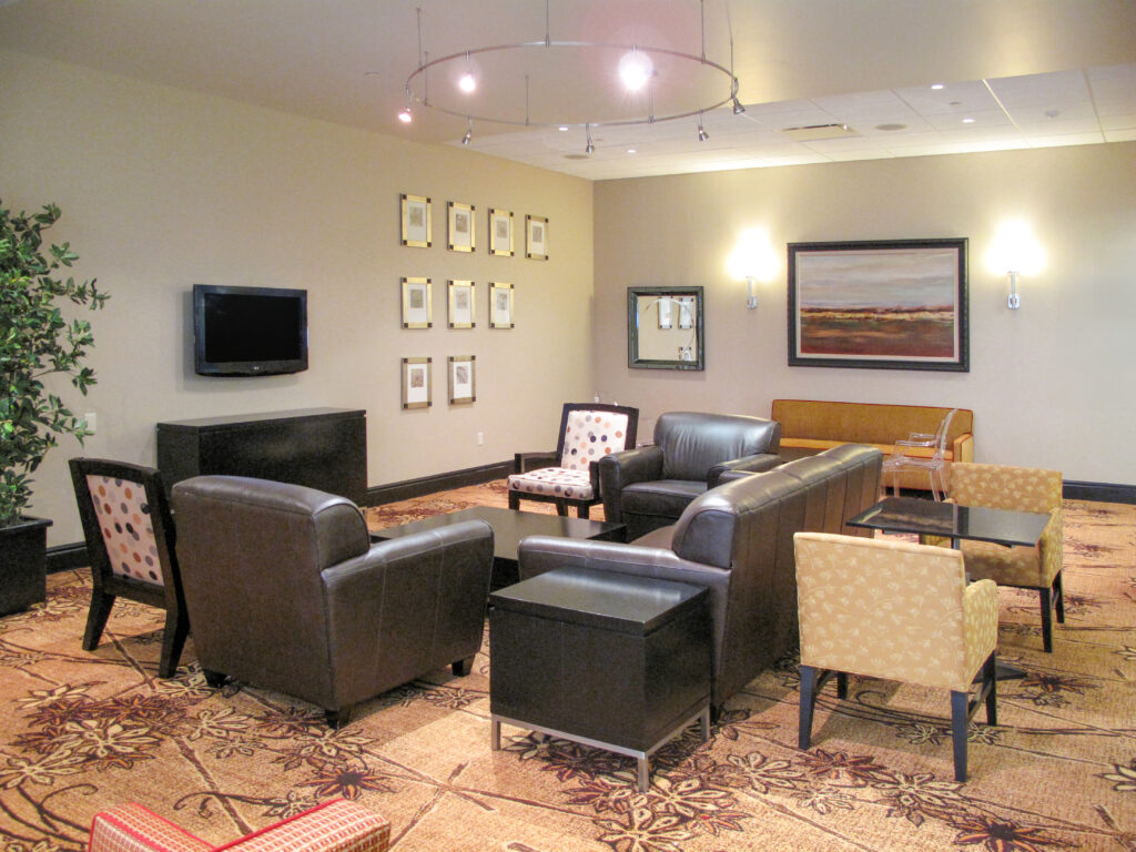 Lobby seating area with dark leather armchairs, patterned side chairs, coffee tables, and framed artwork on the walls.