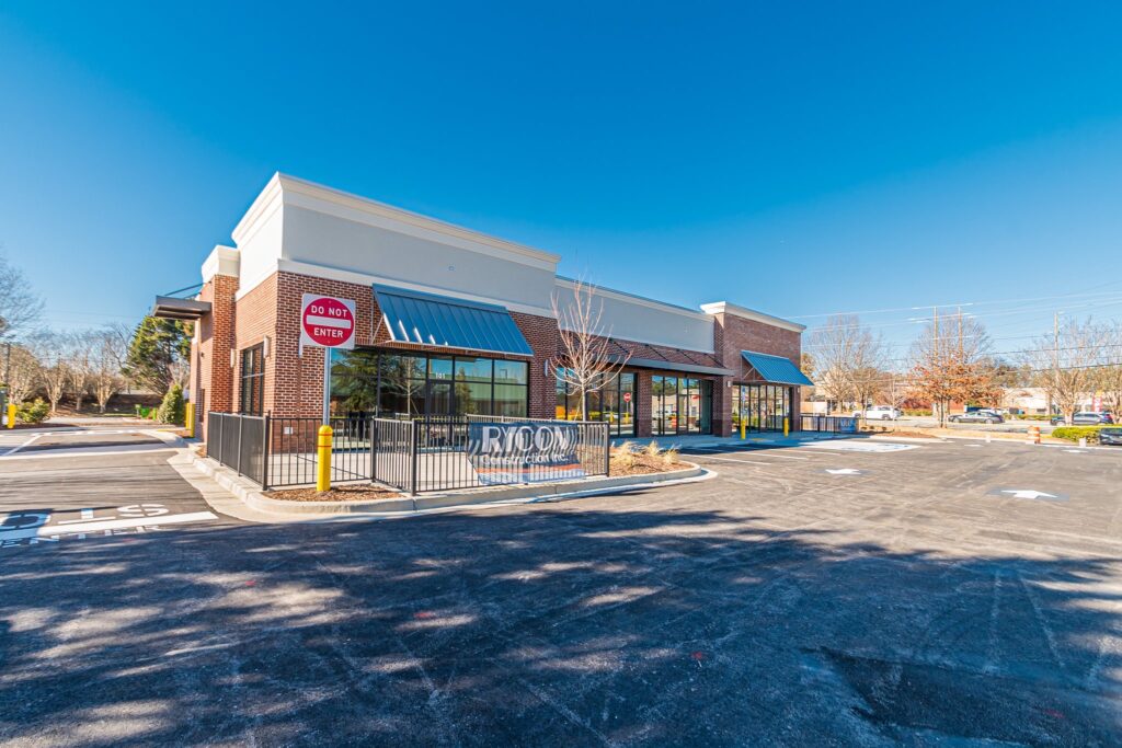 A brick retail building with a parking lot and a Rycon Construction sign in front.