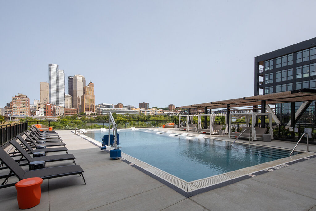 Rooftop swimming pool with lounge chairs and cabanas, overlooking the Pittsburgh skyline.
