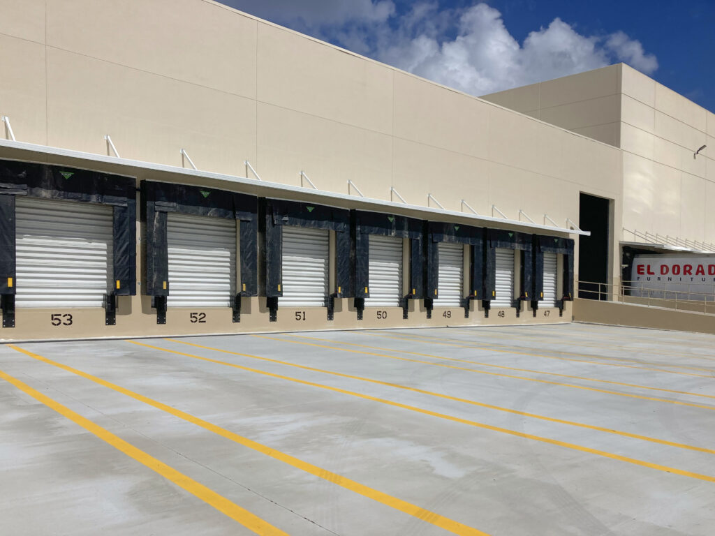 A row of loading docks numbered 47 through 53 on a beige industrial building, with a truck marked “El Dorado Furniture” visible in the background.