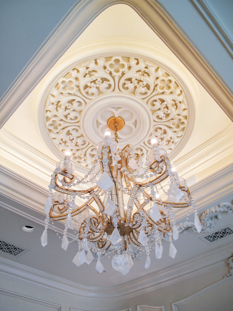 A crystal chandelier hanging from a decorative white ceiling medallion.