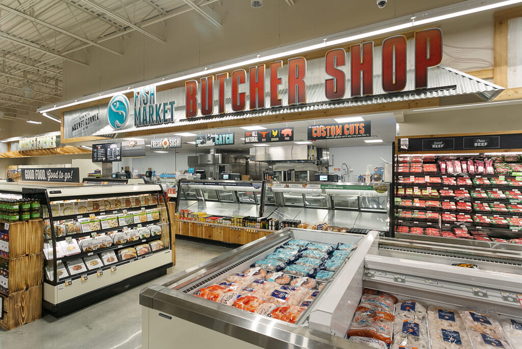 Grocery store butcher shop and fish market counter with refrigerated display cases containing packaged meat and seafood.