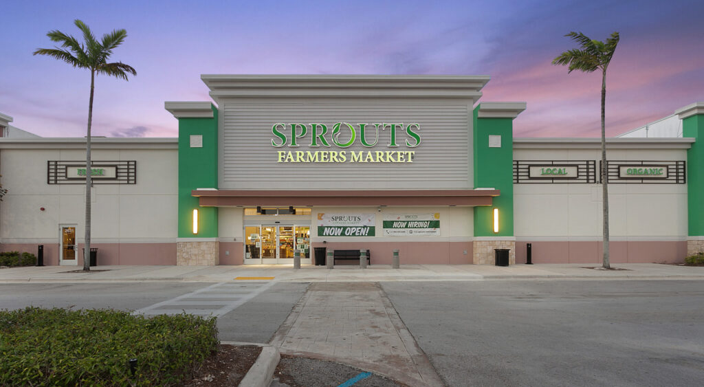 Exterior view of a Sprouts Farmers Market storefront with a “Now Open” sign above the entrance.