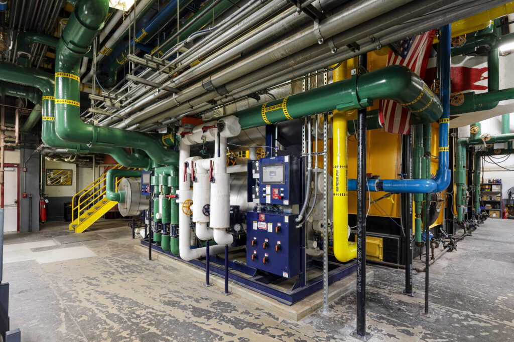 Industrial boiler system with a network of labeled pipes and a digital control panel.