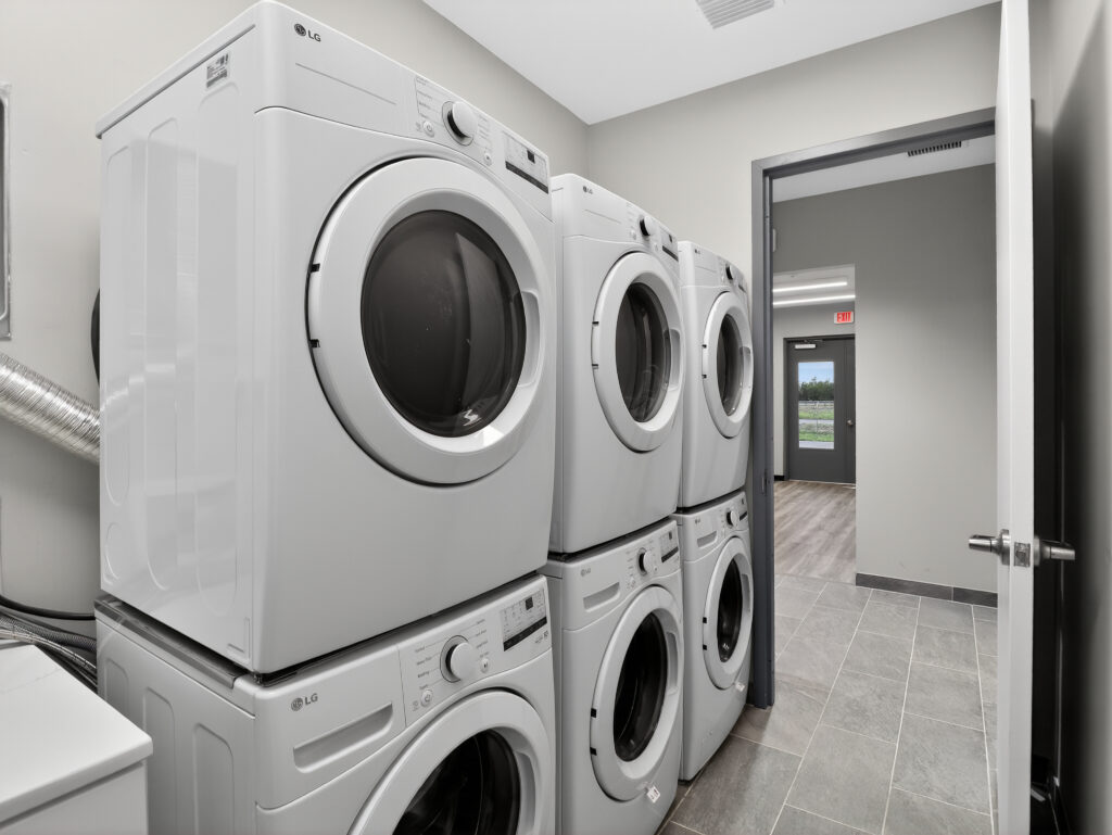 Three stacks of white LG front-loading washers and dryers in a laundry room with tile floors.