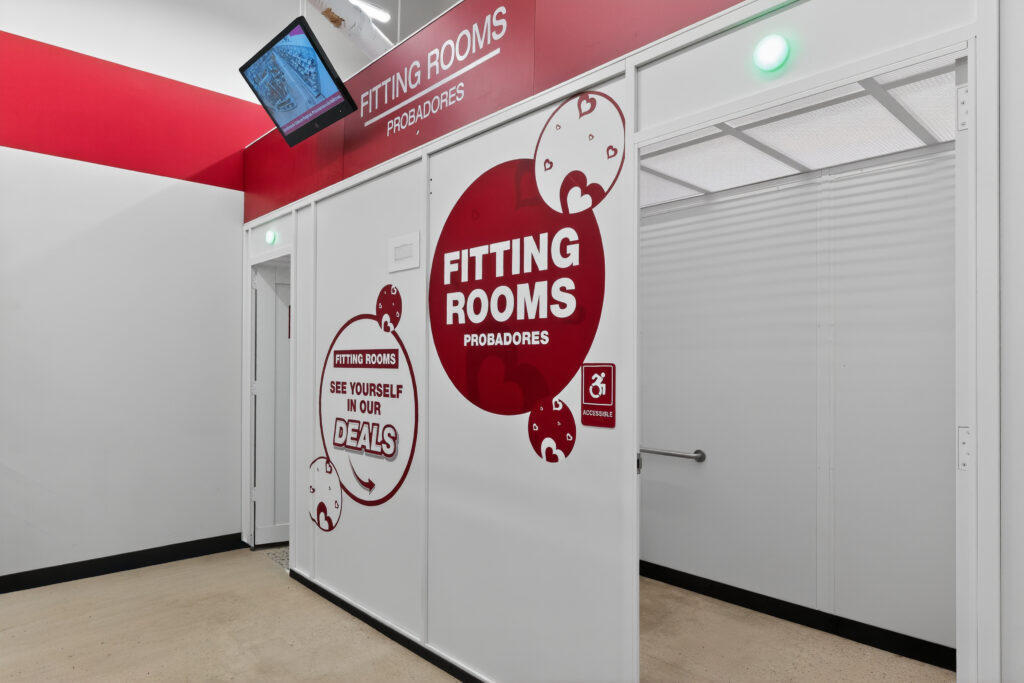 Fitting room area with bilingual signs in English and Spanish, including an accessible stall.
