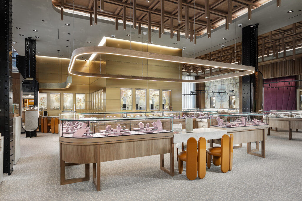 Interior of a high-end jewelry store with curved display cases, wooden accents, and gold-toned wall panels.