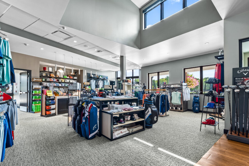 Interior of a golf shop with displays of clubs, apparel, bags, and accessories.