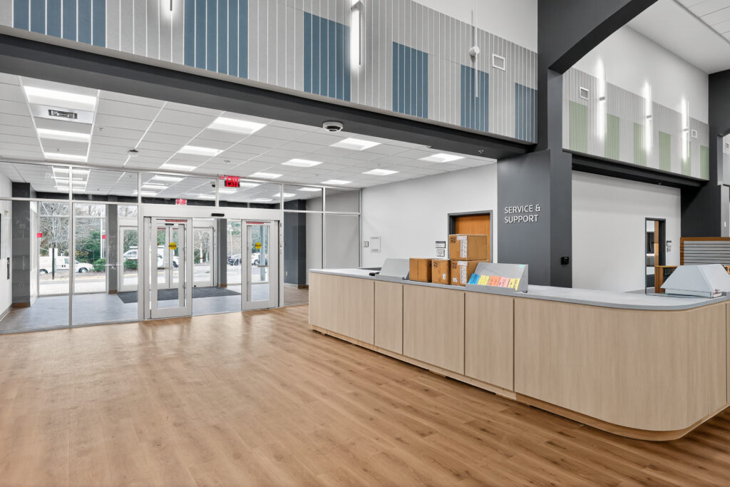 A Service & Support reception desk in a modern lobby with a light wood front, viewed from the entrance.