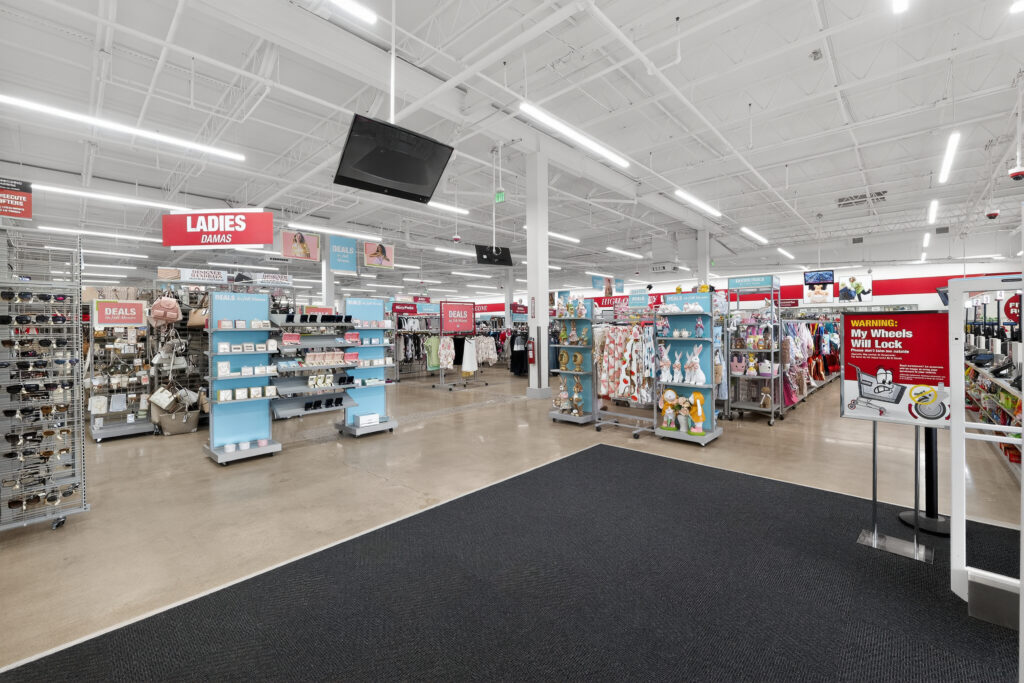 Interior of a retail store with aisles of merchandise, including handbags and Easter decor, under a high industrial ceiling.