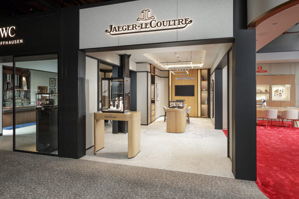 Jaeger-LeCoultre boutique storefront with a display case in the entryway, flanked by an IWC boutique on the left and an Omega boutique on the right.