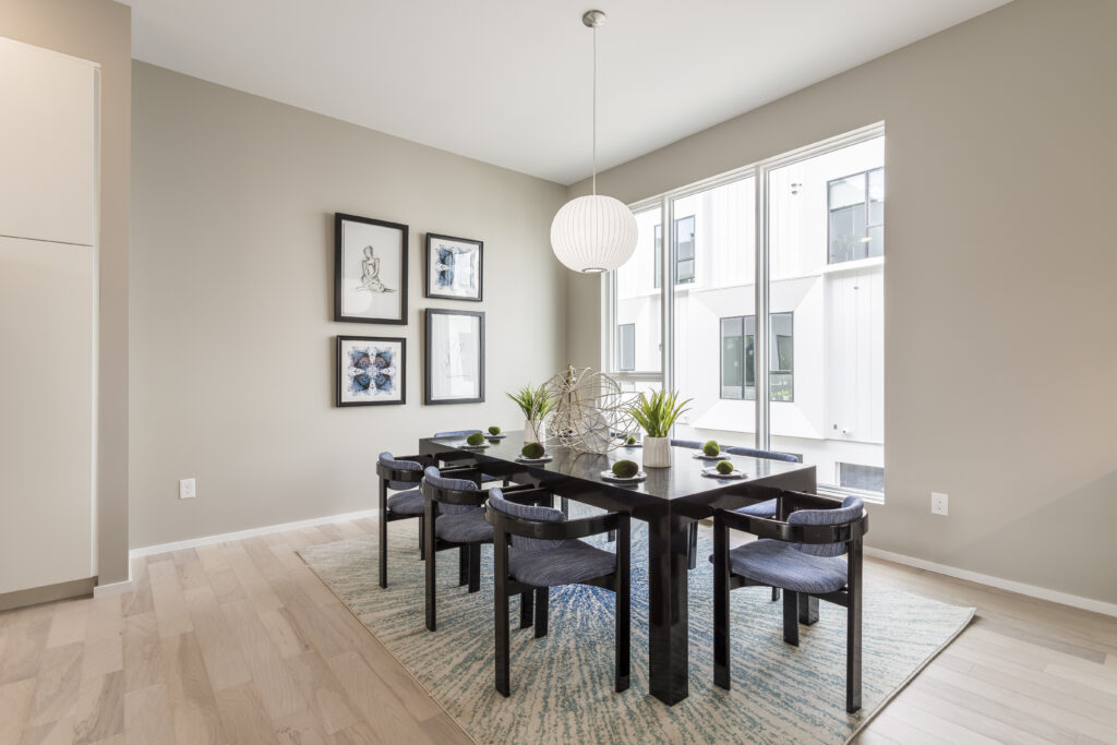 A dark wooden dining table with six blue upholstered chairs, centered under a globe pendant light on a patterned rug.
